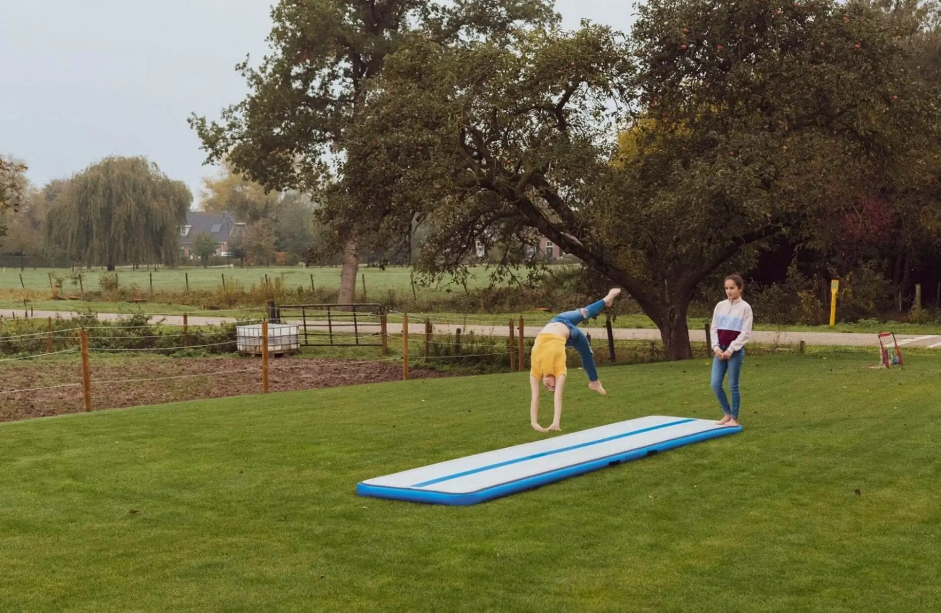 2 girls tumbling outside in garden on blue airfloor home